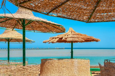 Deniz kıyısı bölgesinde hasır şemsiyeler. El Gouna, Mısır, Kuzey Afrika