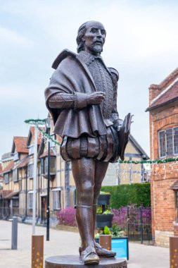 Stratford-upon-Avon, İngiltere - 9 Kasım 2024: William Shakespeare 'in bronz heykeli ve arka plandaki atalarının evi