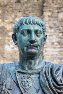 Bronze statue of Roman Emperor Trajan before remains of London Wall. London, England