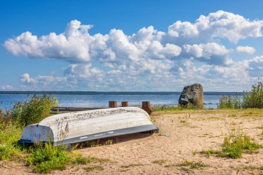 Kasmu köyündeki granit buzulun yanında beyaz bir tekne. Baltık Denizi, Estonya