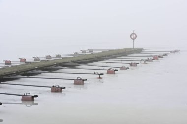 Kışın kar altında gölde boş bir tekne iskelesi. 