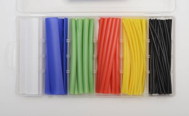 This image displays an organized plastic container holding a variety of heat shrink tubing in different colors. Each compartment contains heat shrink tubes in distinct colors, including white, blue, green, red, yellow, and black. These tubes are used clipart