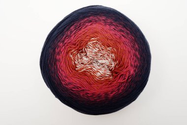 Bu görüntü, dış kenarlarında lacivert renkten koyu kırmızı, bordo ve beyaz tonlarına doğru değişen bir renk değişimi gösteren iplik yumağını gösteriyor. İplik dairesel bir şekilde sıkıca sarılmış. Renk değişkenini net bir şekilde gösteriyor.