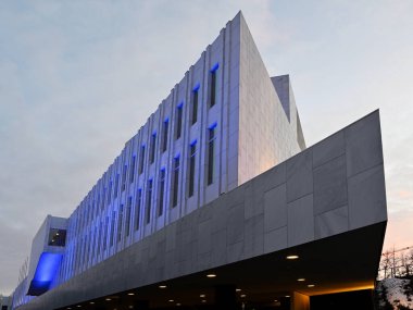 Finlandiya 'nın Helsinki şehrinde bulunan Findia Hall' a dikkat çekici bir bakış açısı, Alvar Aalto 'nun ayırt edici modernist tasarımını sunar. Mermer cephe ve geometrik şekiller mavi ışıkla aydınlatılıyor ve akşam gökyüzüne karşı büyüleyici bir tezat oluşturuyor. Bir 