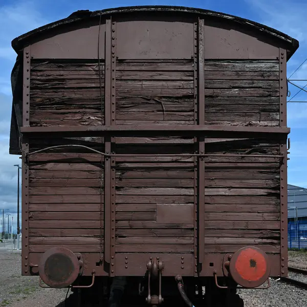 Eski bir ahşap yük vagonunun dikiz görüntüsü, eski, yıpranmış tahta ve paslanmış metal parçaların ham dokusunu gösteriyor. Muhtemelen Finlandiya 'da bir demiryolu müzesinde ya da tren istasyonunda bulunan vagonda uzun süreli maruz kalma belirtileri gösterilir.