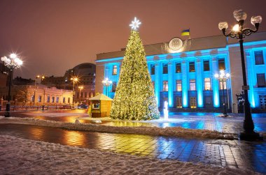 Karlı gecelerde süslemeleri ve aydınlatmaları olan büyük, güzel bir Noel Ağacı. Yılbaşı ve Noel tatili geçmişi. Şenlikli kış şehri manzarası.