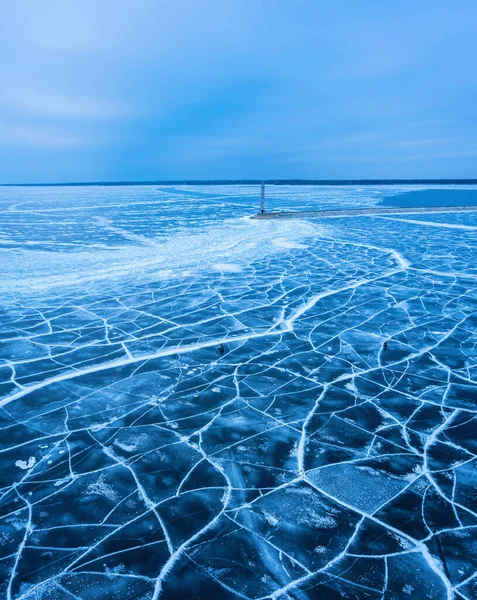 stock image aerial view of a lonely lighthouse in the frozen sea. Frozen blue ice in cracks, drone view