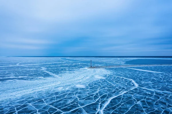在冰冷的大海中的一座孤寂的灯塔的鸟瞰图 裂缝中结冰的蓝色冰 无人视线 — 图库照片