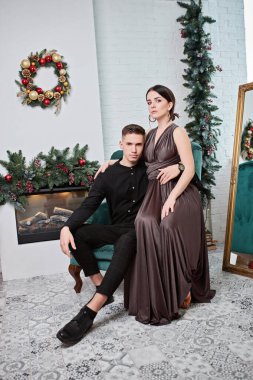 Genç çift Noel ağacının yanında poz veriyor ve sarılıyorlar.