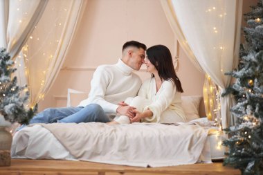 Aşk evde hediye ağacıyla yakınındaki Aralık ayında Noel arifesi öpüşme içinde genç tatlı güzel Çift.