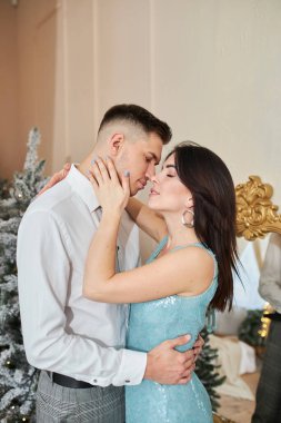 Aşık güzel bir çift. Zarif gece kıyafetleri içinde neşeli genç bir çift. Moda, cazibe. İç dekore edilmiş Noel 'de kucaklaşan çift