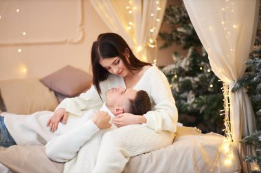 Aşk evde hediye ağacıyla yakınındaki Aralık ayında Noel arifesi öpüşme içinde genç tatlı güzel Çift.