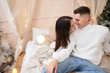 Genç çift Noel ağacının yanında poz veriyor ve sarılıyorlar.