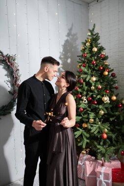 Aşık güzel bir çift. Zarif gece kıyafetleri içinde neşeli genç bir çift. Moda, cazibe. İç dekore edilmiş Noel 'de kucaklaşan çift 