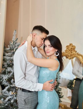 Aşık güzel bir çift. Zarif gece kıyafetleri içinde neşeli genç bir çift. Moda, cazibe. İç dekore edilmiş Noel 'de kucaklaşan çift