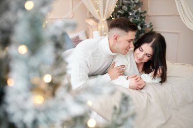 Gülümseyen sevimli kız arkadaşı, erkek arkadaşıyla olmaktan ve birbirleriyle iletişim kurmaktan mutlu. Olumlu romantik çift, kış tatili boyunca rahat bir şekilde yataklarında dinleniyor.