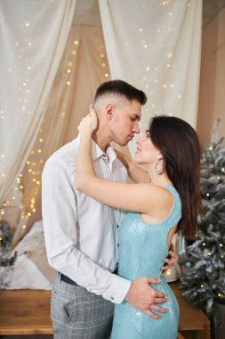 Aşık güzel bir çift. Zarif gece kıyafetleri içinde neşeli genç bir çift. Moda, cazibe. İç dekore edilmiş Noel 'de kucaklaşan çift