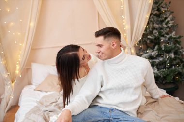 Genç çift Noel ağacının yanında poz veriyor ve sarılıyorlar.