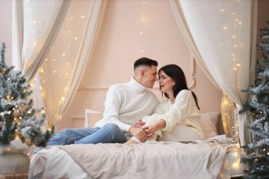 Aşk evde hediye ağacıyla yakınındaki Aralık ayında Noel arifesi öpüşme içinde genç tatlı güzel Çift.