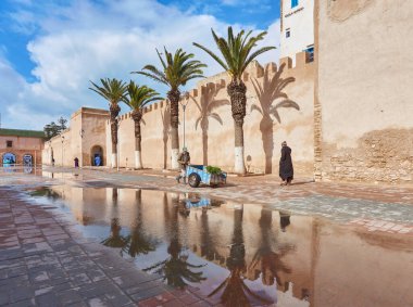ESSAOUIRA, MOROCCO. 13 th February, 2017: Ancient walls of the medina, merchants hurrying on business, after the rain