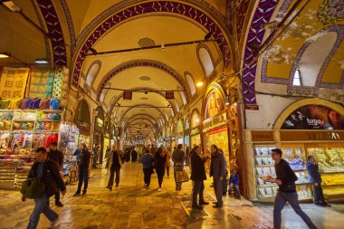 ISTANBUL - APRIL 21, 2017: People shopping in the Grand Bazar, handmade pillows, bags and carpets are on the wall for sale. 