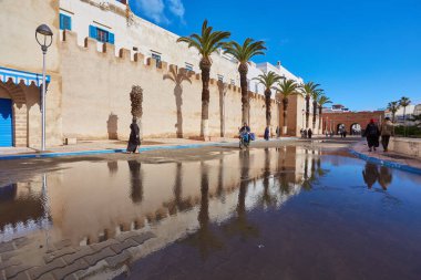 ESSAOUIRA, MOROCCO. 13 th February, 2017: Ancient walls of the medina, merchants hurrying on business, after the rain