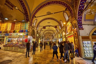 ISTANBUL - APRIL 21, 2017: People shopping in the Grand Bazar, handmade pillows, bags and carpets are on the wall for sale. 