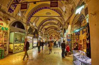 ISTANBUL - APRIL 21, 2017: People shopping in the Grand Bazar, handmade pillows, bags and carpets are on the wall for sale. 