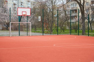 Empty school stadium with synthetic green field and red treadmills in rainy weather outside