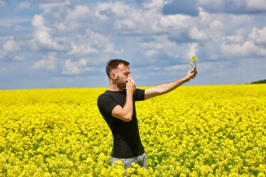 man in field blowing his nose and suffering from hay fever. Allergy clipart