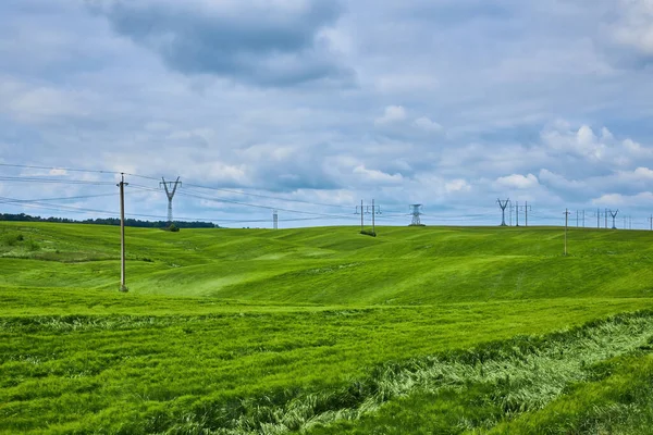 昼間は緑の小麦畑の電柱 再生可能エネルギーの輸送 — ストック写真