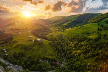 Yazın gün doğumunda bulutların içinde dağlar. Siste yeşil ağaçlar olan dağ zirvesinin havadan görünüşü. Yüksek kayalar, orman ve gökyüzü olan güzel bir manzara. Dağ vadisinin alçak bulutlu insansız hava aracı manzarası