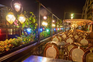 Venedik, İtalya 'da köprü ve restoran masaları olan bir cadde. Venedik 'in mimarisi ve simgesi. Venedik 'in gece sıcacık şehri.