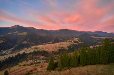 Dağ ormanı, akşam gökyüzü altında güneş ışığında bulutlarla kaplı. Hava aracı görünümü.