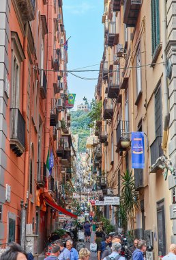 Napoli, İtalya - 25 Ekim 2019 - Şehir sakinleri tarihi Centro Storico şehir merkezinin dar çamaşırhaneli caddesinde park halindeki araçlar arasında yürürler..