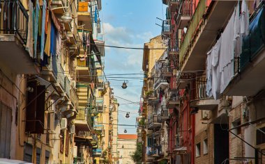 Napoli, İtalya - 25 Ekim 2019 - Şehir sakinleri tarihi Centro Storico şehir merkezinin dar çamaşırhaneli caddesinde park halindeki araçlar arasında yürürler..