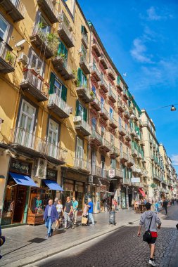 Napoli, İtalya - 25 Ekim 2019 - Şehir sakinleri tarihi Centro Storico şehir merkezinin dar çamaşırhaneli caddesinde park halindeki araçlar arasında yürürler..