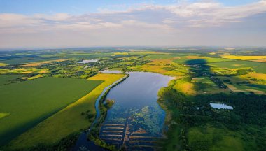 Geniş nehrin havadan manzarası yaz akşamları yeşil tarlalar arasında kırsal alanda sessizce akıyor.
