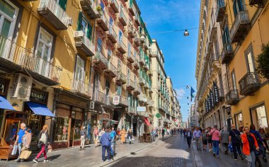 Napoli, İtalya - 25 Ekim 2019 - Şehir sakinleri tarihi Centro Storico şehir merkezinin dar çamaşırhaneli caddesinde park halindeki araçlar arasında yürürler..
