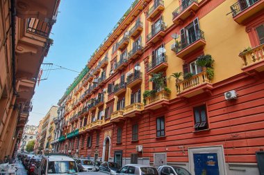 Napoli, İtalya - 25 Ekim 2019 - Şehir sakinleri tarihi Centro Storico şehir merkezinin dar çamaşırhaneli caddesinde park halindeki araçlar arasında yürürler..