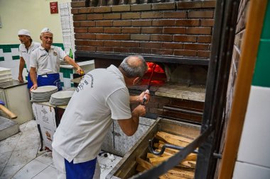 Napoli, İtalya - 24 Ekim 2019: MICHELIN Kılavuzu İtalya. L'Antica Pizzeria da Michele. Napoli pizzacısı. Napoli, İtalya. Ahşap fırında Napoli pizzası yapan bir adam. Küreğin üstünde pizza vardı..