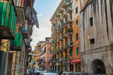 Napoli, İtalya - 25 Ekim 2019 - Şehir sakinleri tarihi Centro Storico şehir merkezinin dar çamaşırhaneli caddesinde park halindeki araçlar arasında yürürler..