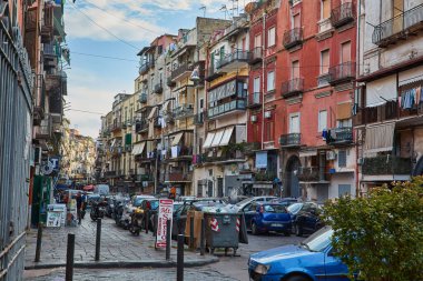 Napoli, İtalya - 25 Ekim 2019: Şehir sakinleri tarihi Centro Storico şehir merkezinin dar çamaşırhaneli caddesinde park halindeki arabaların arasında yürüyor.