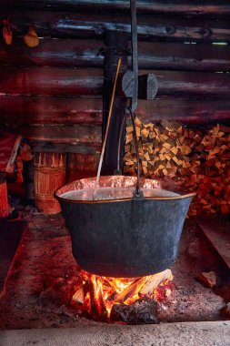 Açık ateşte peynirin pişirildiği büyük bir fıçı. Siyah kazan açık bir odun ateşinin üzerinde hazırlanıyor. Dağlardaki peynir fabrikası.