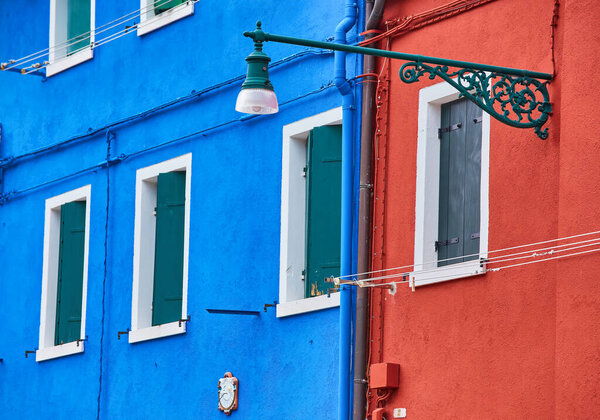Burano island, traditional colourful walls of the common old houses and a street lantern, architectural background.