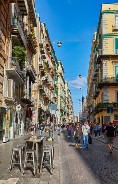 Napoli, İtalya - 25 Ekim 2019 - Şehir sakinleri tarihi Centro Storico şehir merkezinin dar çamaşırhaneli caddesinde park halindeki araçlar arasında yürürler..