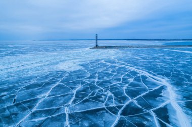Kışın Baltık Denizi 'ne dökülen dalgalar. Sis ve buz bloklarıyla kaplı deniz. Güneşin doğuşunda güzel deniz feneri.