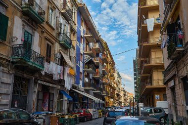 Napoli, İtalya - 25 Ekim 2019 - Şehir sakinleri tarihi Centro Storico şehir merkezinin dar çamaşırhaneli caddesinde park halindeki araçlar arasında yürürler..
