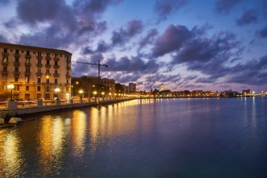 Bari, İtalya 'da deniz önü ve gezinti güvertesinde boş bank ve lamba direkleri. Romantik, sakin, rahatlatıcı bir akşam. Güneş batıyor.