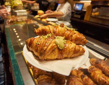Yakın görüş - yeni pişmiş kruvasanların tezgahta, markette, kafede veya fırında satışı. Tatlı, pasta, kahvaltı, tatlı yemek ve geleneksel Fransız mutfağı konsepti.